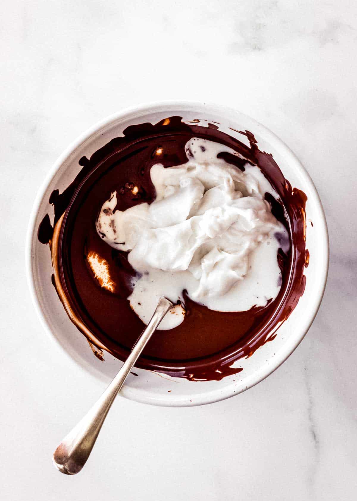 Melted dark chocolate and coconut cream are mixed together in a small bowl.