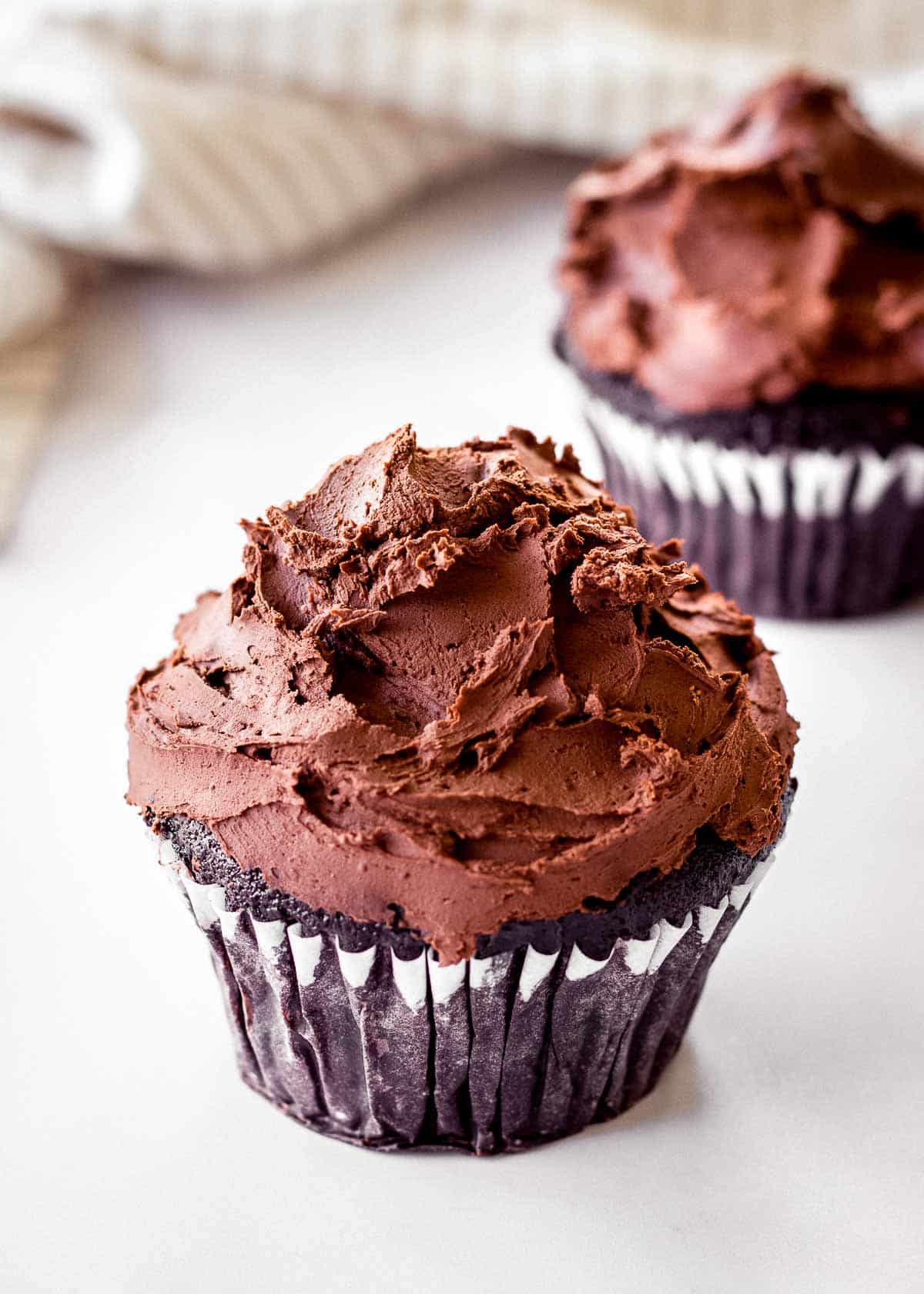 Two chocolate cupcakes decorated with vegan dark chocolate ganache.
