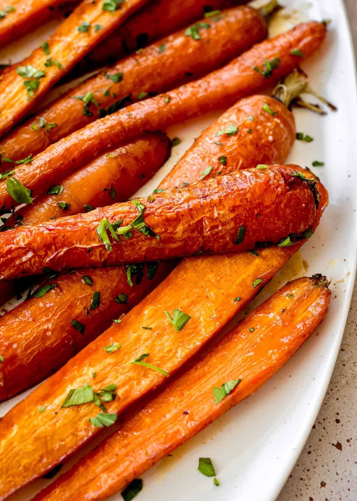 Maple roasted carrots on a white plate sprinkled with parsley.