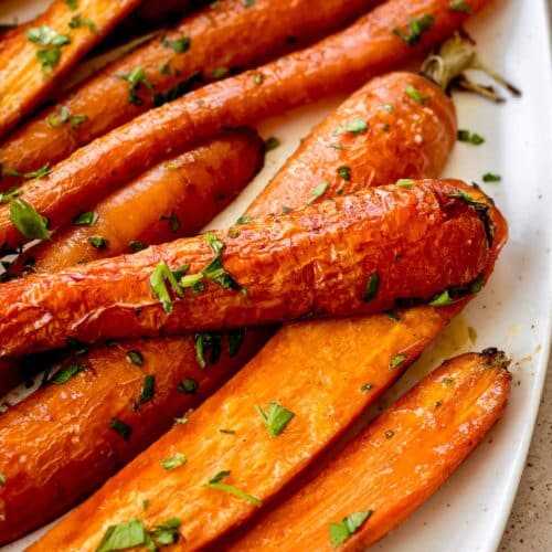 Maple roasted carrots on a white plate sprinkled with parsley.