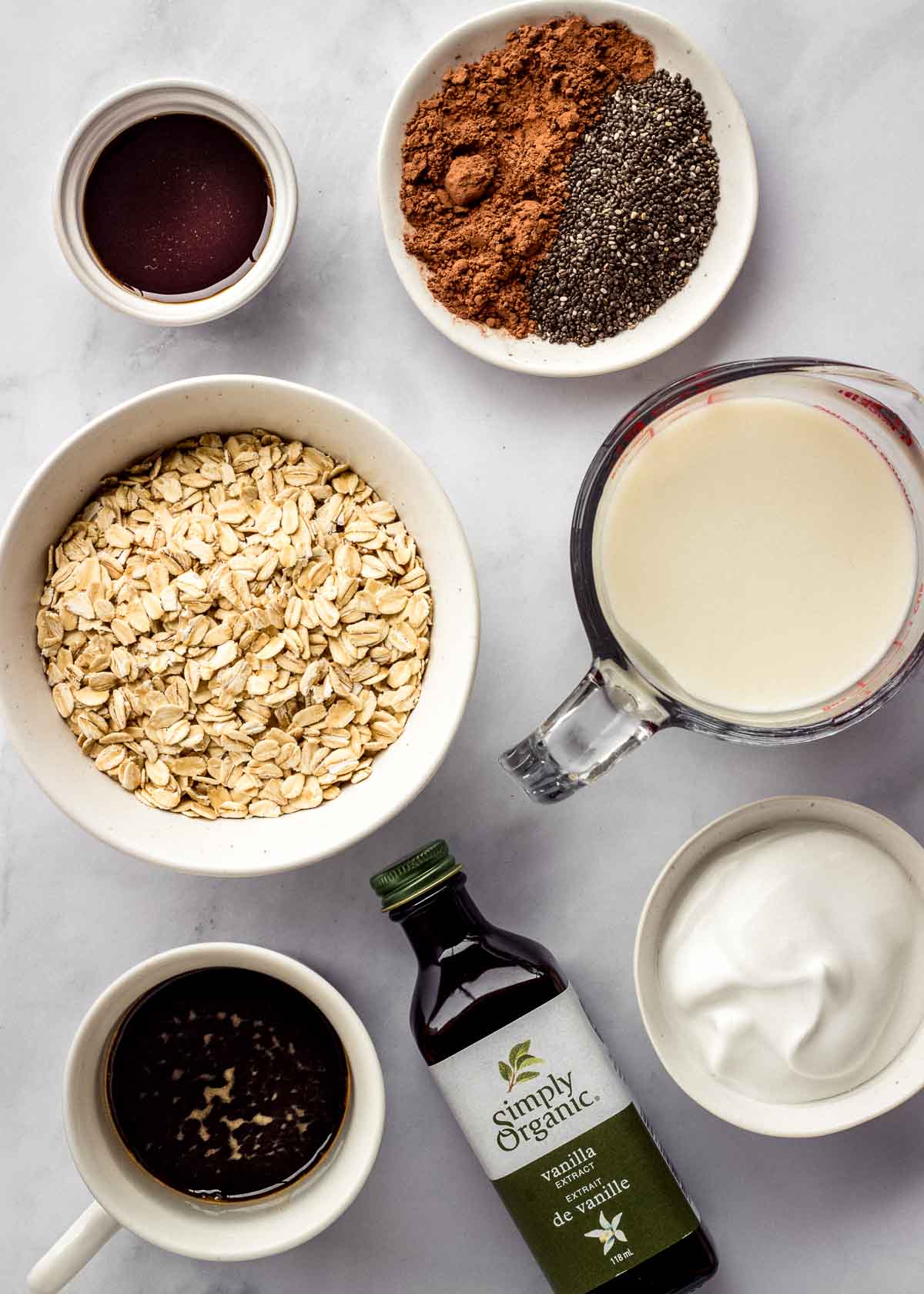Ingredients for tiramisu overnight oats: oats, vanilla, cocoa powder, chia seeds, espresso, maple syrup, oat milk and coconut yoghurt.