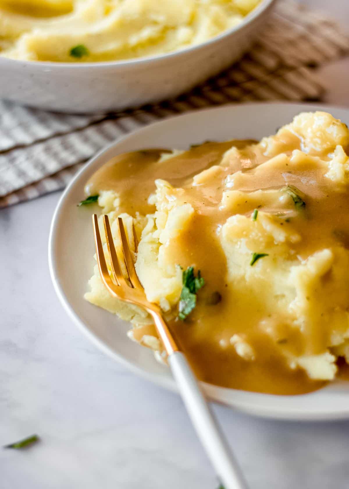 A plate of mashed potatoes and seriously easy vegan gravy with a golden fork.