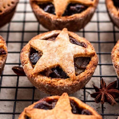 Vegan mince pies with pastry stars on top, on a black cooling rack.