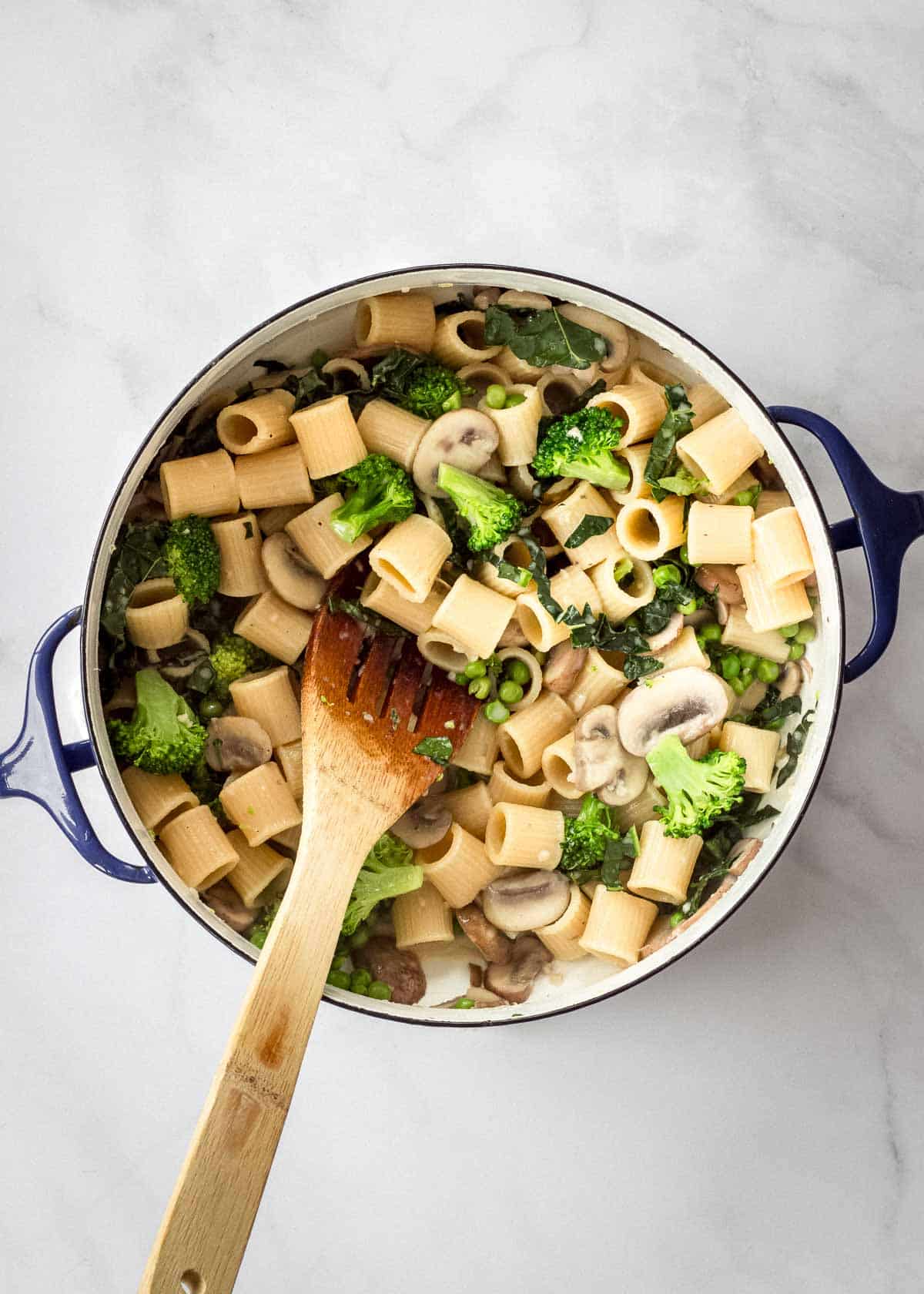 Large pot containing pasta with mushrooms and broccoli being cooked.