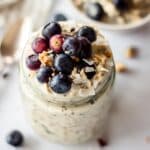 Mason jar of blueberry overnight oats, topped with blueberries, coconut and granola.