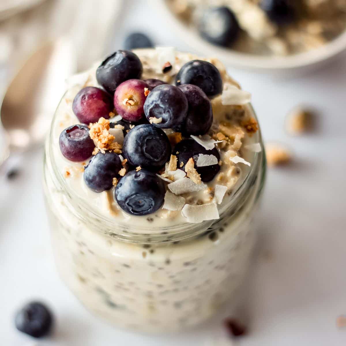 Glass jar of blueberry overnight oats decorated with blueberries and granola.