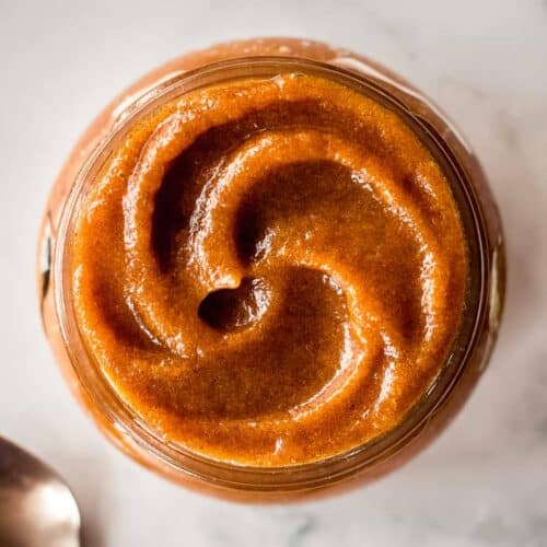 Glass jar of date paste, forming a swirl on top.