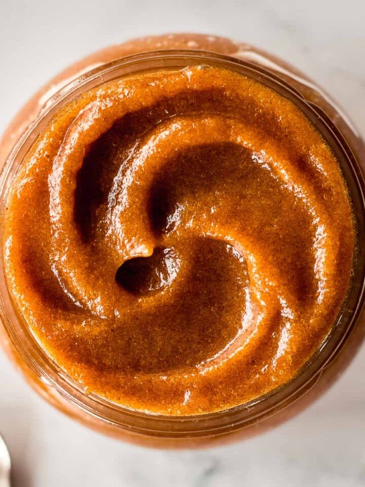 Glass jar of date paste, forming a swirl on top.