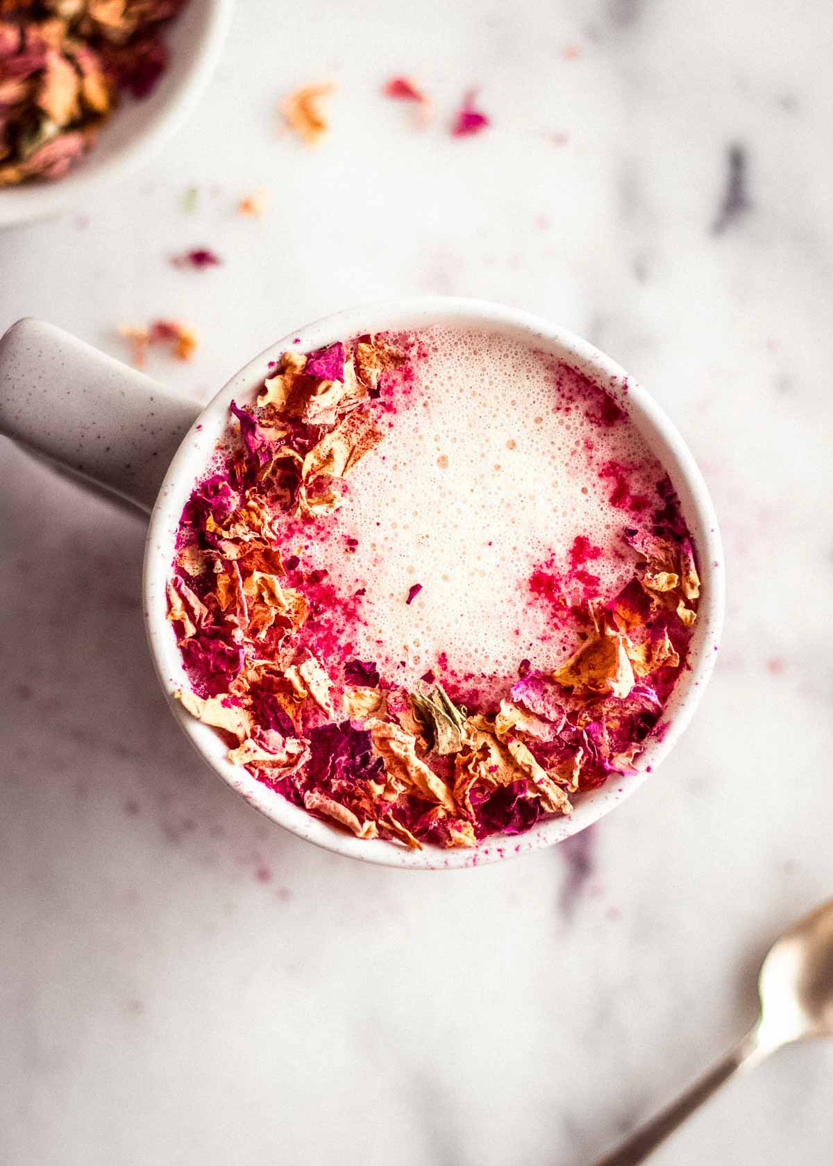 Overhead shot of rose latte decorated with rose petals.