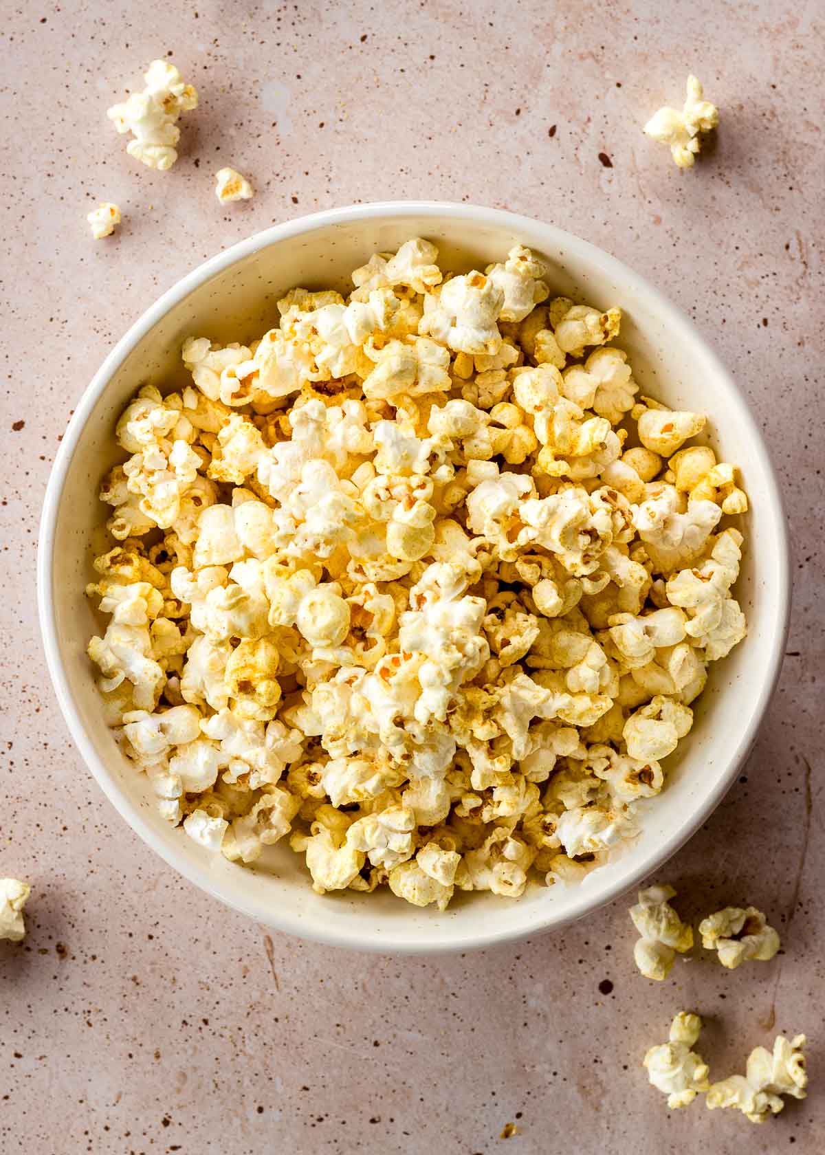 Vegan popcorn in a white bowl, with a dairy free cheese seasoning.