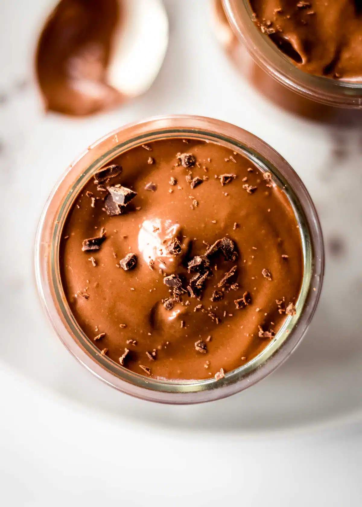 Glass pot of avocado chocolate mousse topped with grated chocolate.