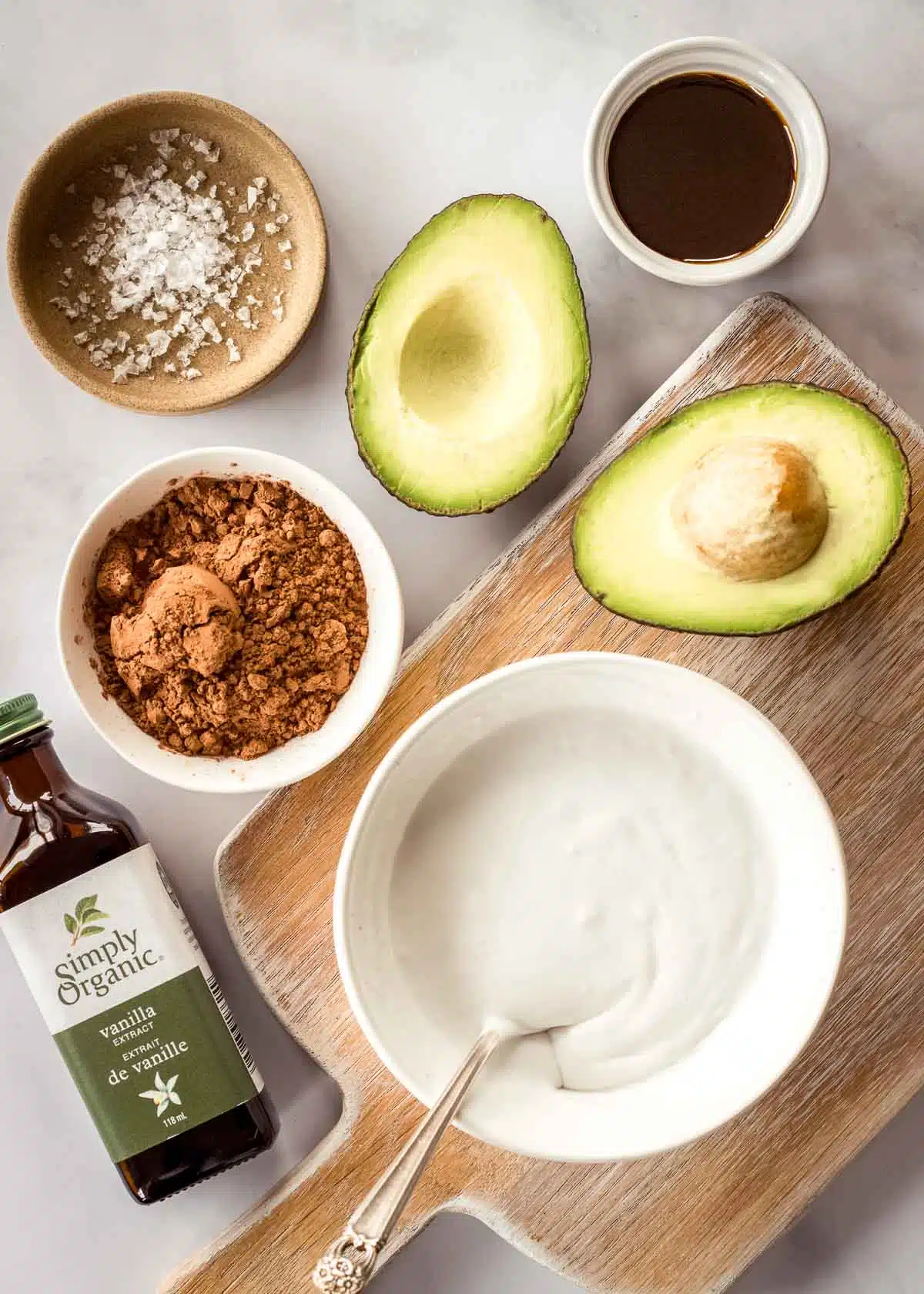 Ingredients for avocado chocolate mousse, including cacao, coconut milk, vanilla extract and maple syrup.