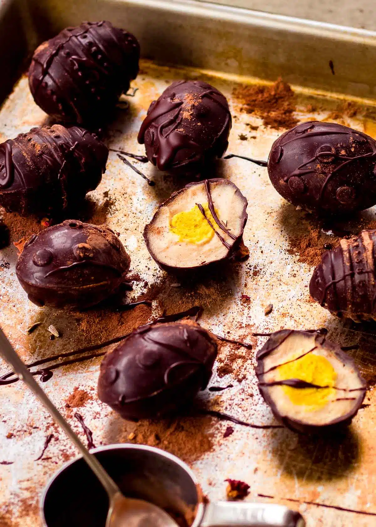 Vegan creme eggs on baking tray drizzled with dark chocolate.