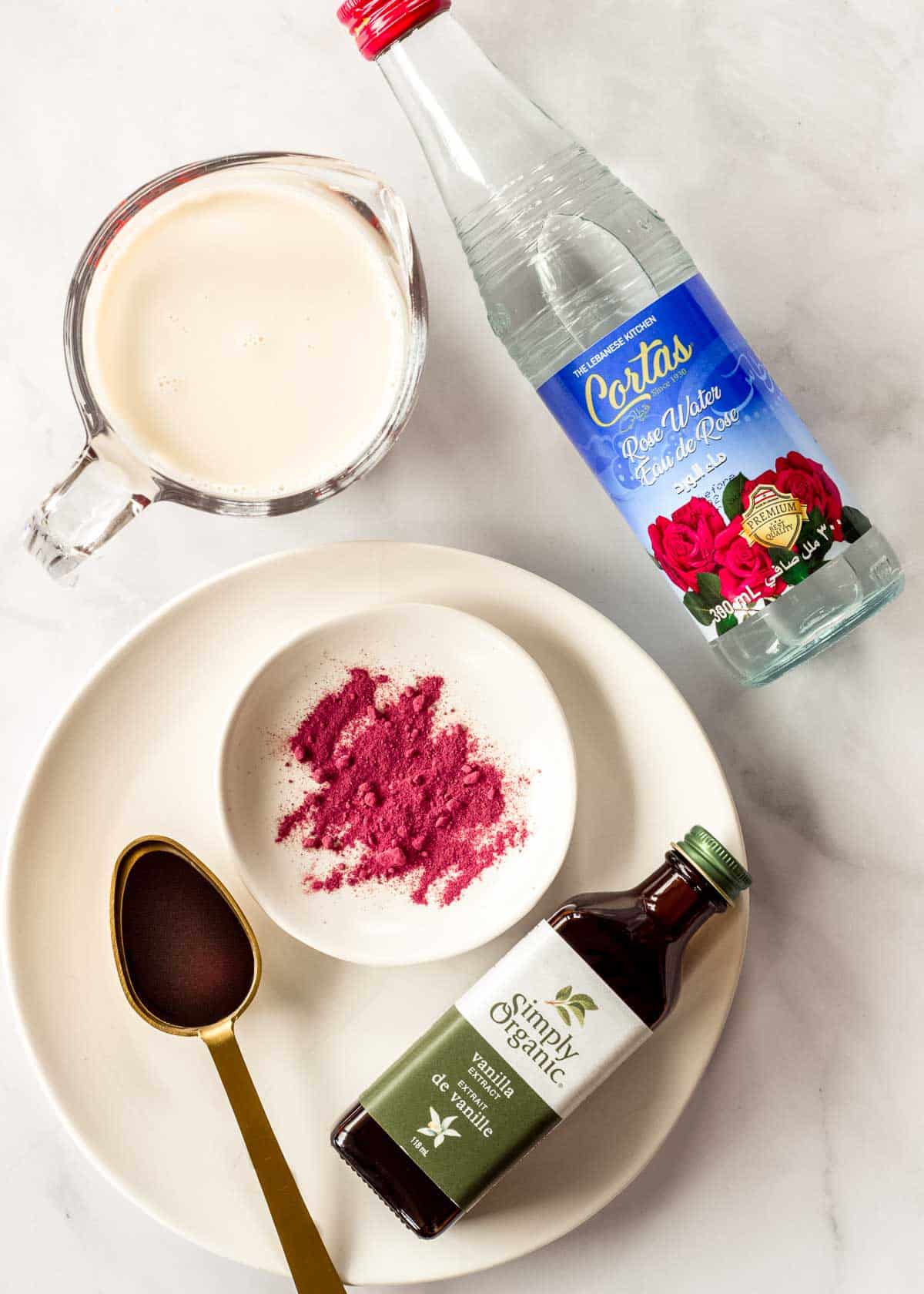 Ingredients to make a rose latte, including beet powder, rose water, vanilla extract and milk.